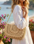 Woman in a white dress holding a woven handbag with a scenic background