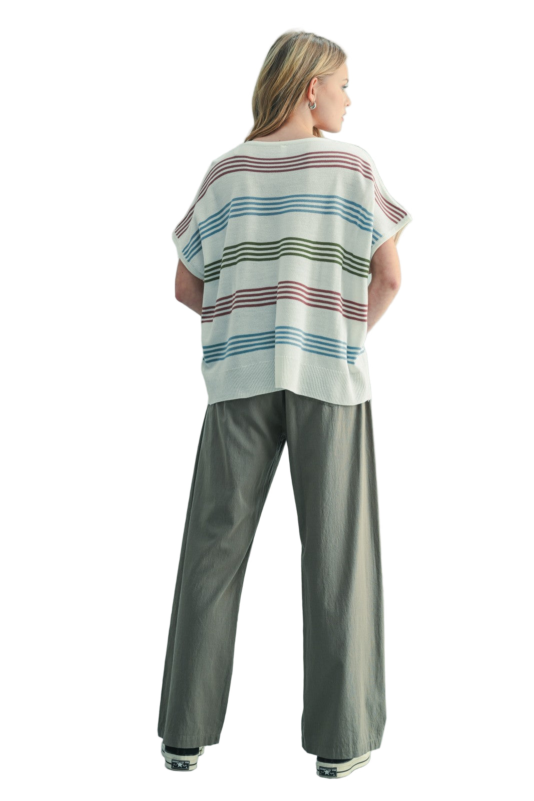 Person wearing a striped shirt and gray pants against a light blue background