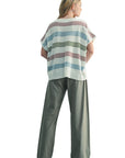 Person wearing a striped shirt and gray pants against a light blue background