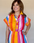 Woman wearing a colorful striped dress against a plain background