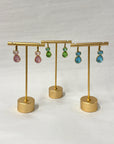 Gold earring stand with colorful earrings on a white background