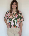 a woman wearing a green floral split neck short sleeve blouse.