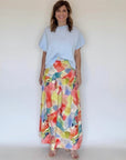 A woman wearing a yellow watercolor print skirt and a blue sweater blouse.