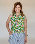 Woman wearing a sleeveless floral top and striped shorts against a plain background