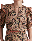 Person wearing a paisley patterned blouse with puff sleeves on a white background