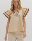Woman wearing a beige blouse with decorative sleeves on a white background