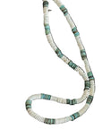Necklace with green and white beads on a dark surface