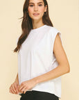 Woman wearing a white sleeveless top against a beige background