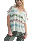 Woman wearing a striped top and pants against a light background