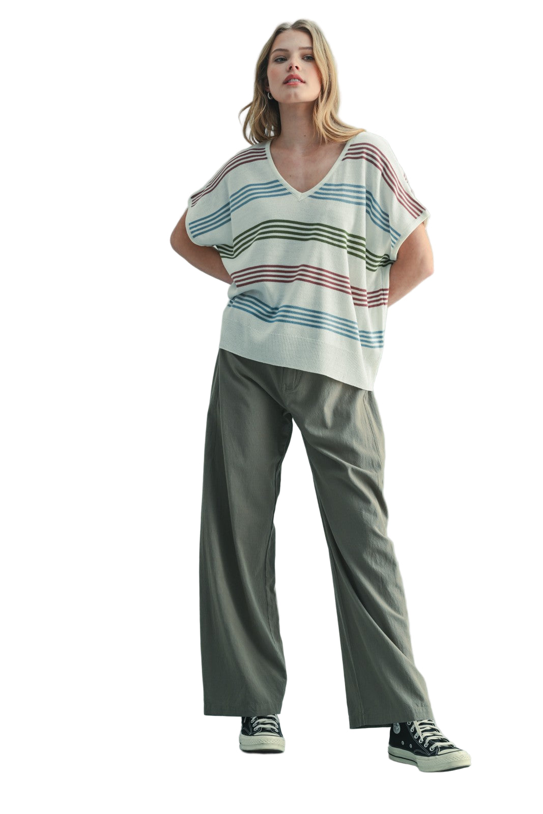 Woman wearing a striped shirt and wide-leg pants against a plain background