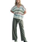 Woman wearing a striped shirt and wide-leg pants against a plain background
