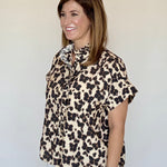 A model posing in the Cheetah Print Blouse, an ecru blouse with a brown and black cheetah print, from Chatsworth Boutique in Fairhope, Alabama.