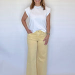 Woman wearing a white top and yellow pants against a white background