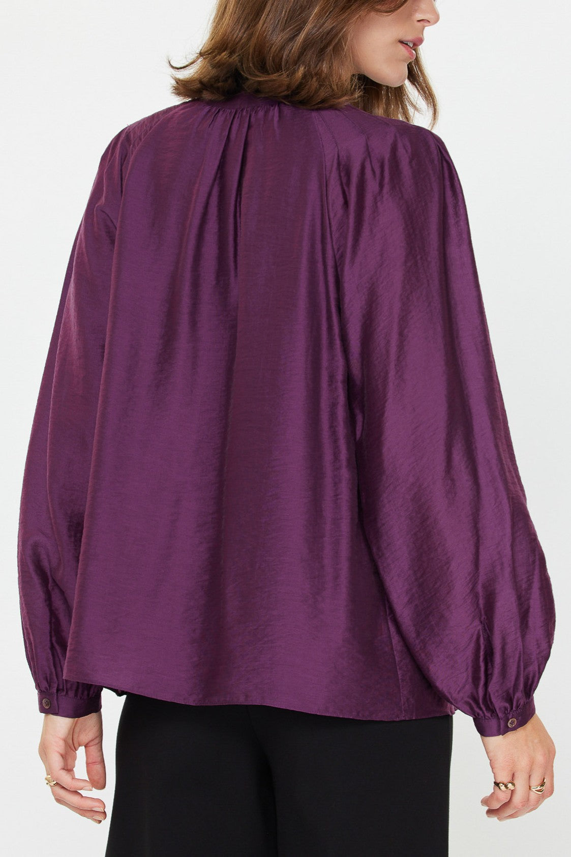 The pleated collar back of a Purple long sleeve silky blouse 
