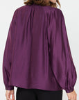 The pleated collar back of a Purple long sleeve silky blouse 
