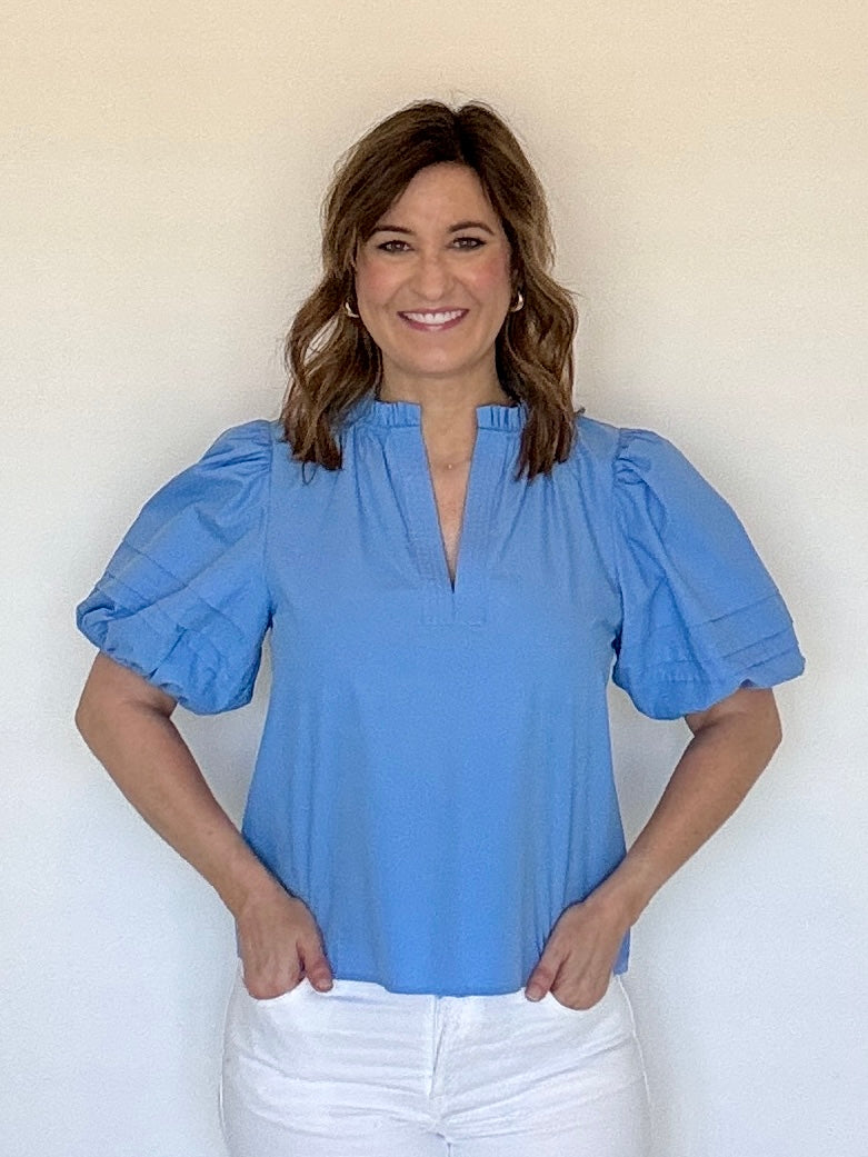 A woman wearing a split neck puff sleeve blue blouse