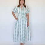 Woman wearing an aqua and white patterned dress against a plain background