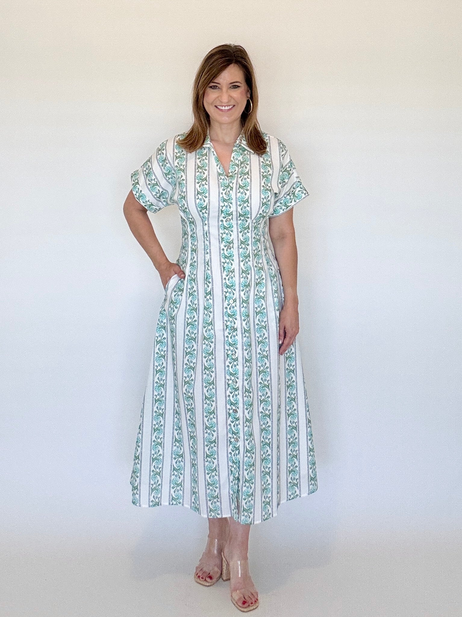 Woman wearing an aqua and white patterned dress against a plain background
