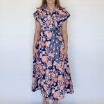 Woman wearing a navy and orange floral dress against a white background