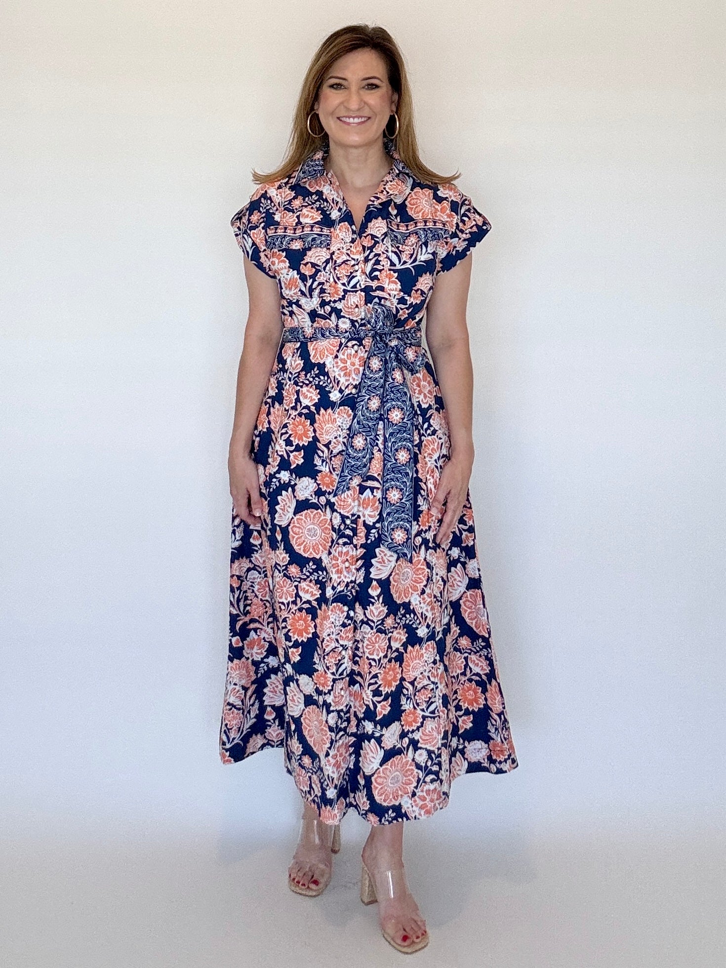 Woman wearing a navy and orange floral dress against a white background