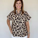 A model wearing the Cheetah Print Blouse, an ecru button-up with a brown and black cheetah print and ruffle collar, from Chatsworth Boutique in Fairhope, Alabama.