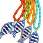 Colorful beaded necklaces with fish-shaped pendants on a beige background