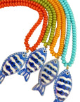 Colorful beaded necklaces with fish-shaped pendants on a beige background