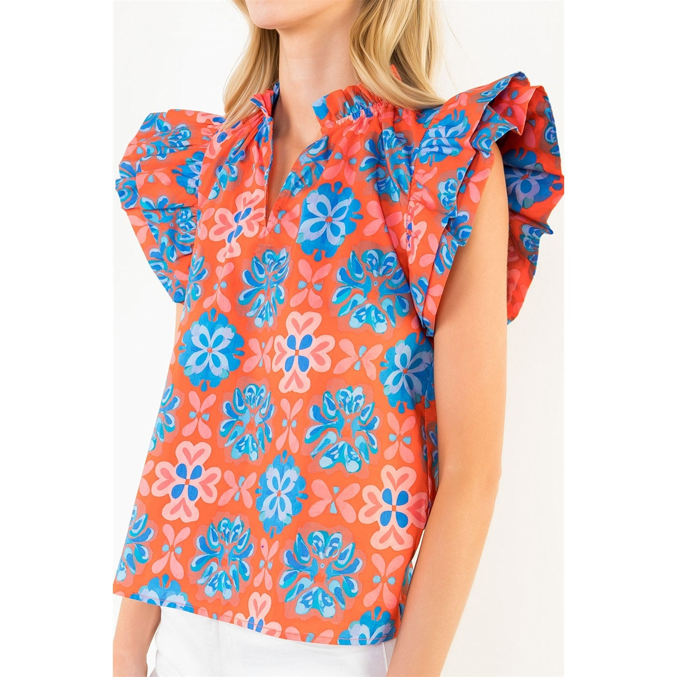 Woman wearing a colorful floral blouse with ruffled sleeves on a white background