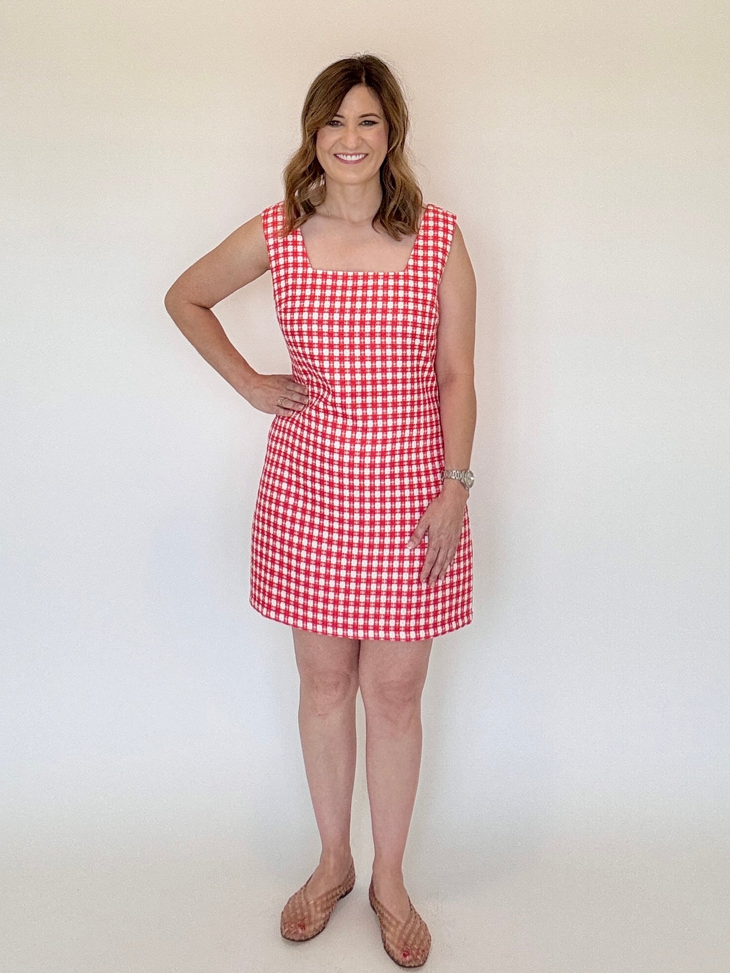 Woman wearing a red and white checkered dress against a plain background