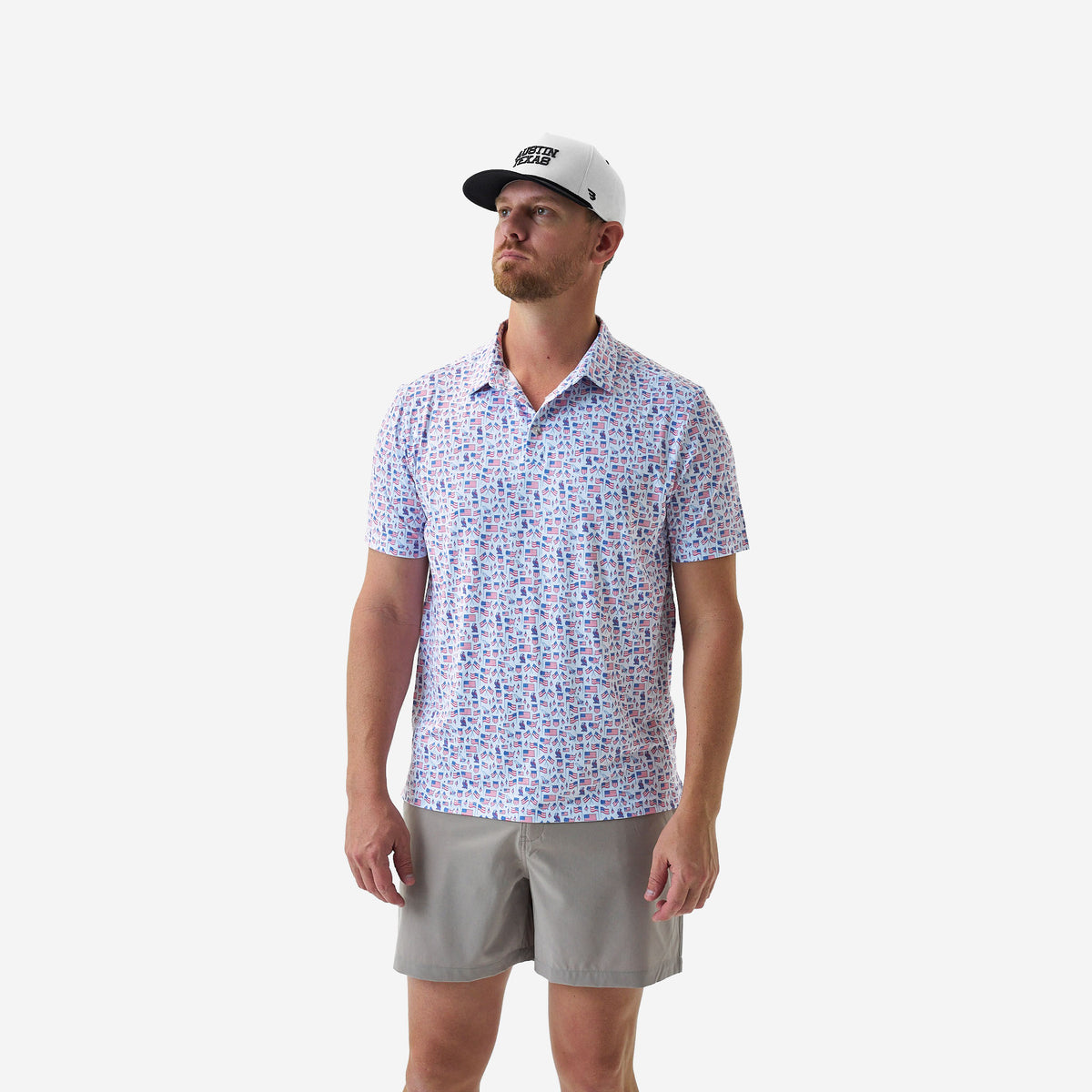 Man wearing a American flag patterned polo shirt and gray shorts on a white background
