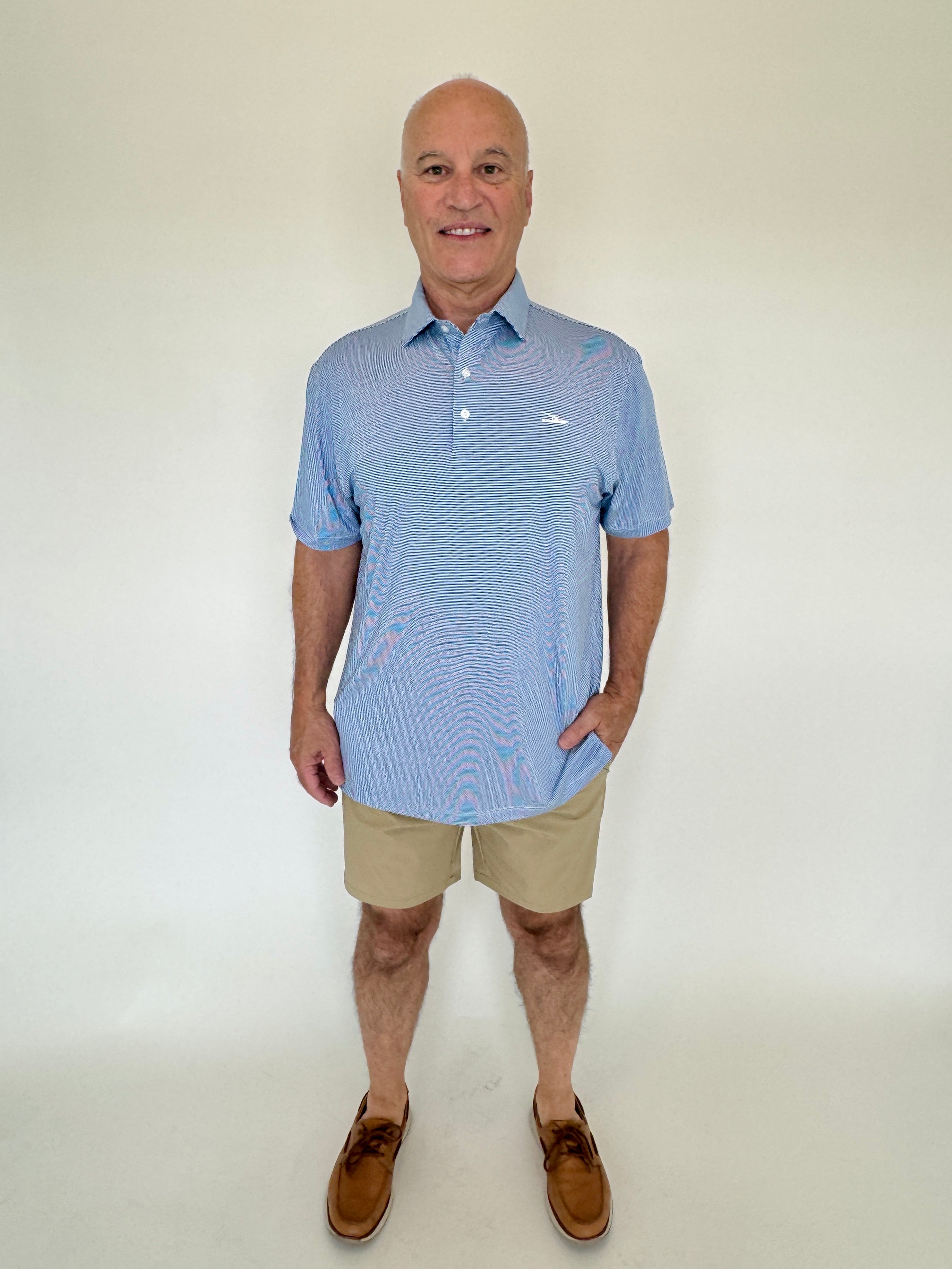 Man wearing a blue striped polo shirt and beige shorts against a white background