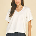 Woman wearing a white t-shirt and dark pants on a beige background
