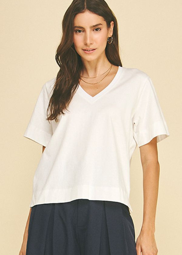 Woman wearing a white t-shirt and dark pants on a beige background