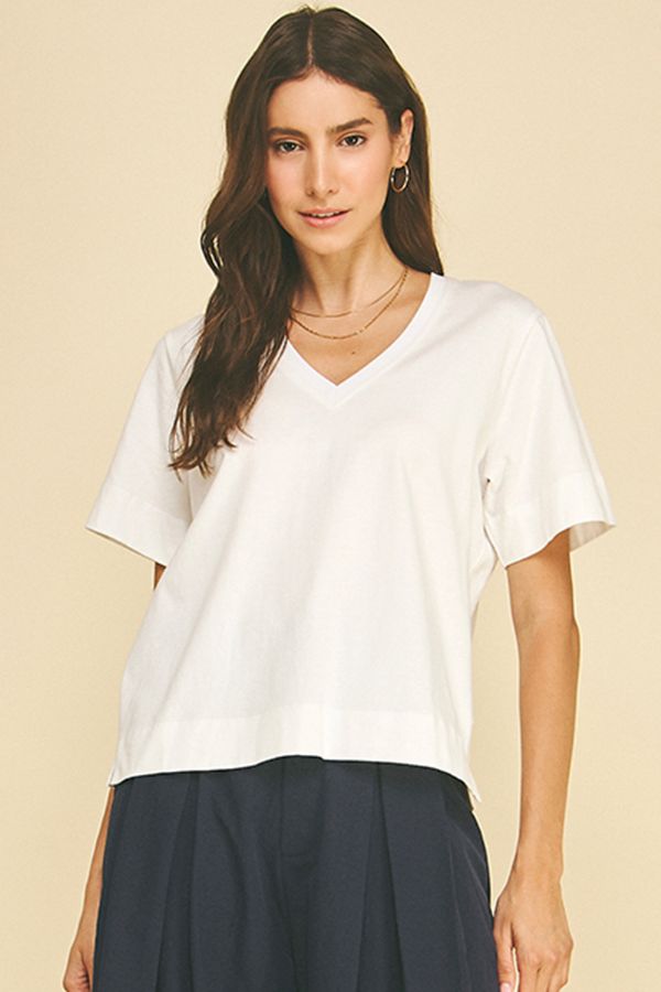 Woman wearing a white t-shirt and dark pants on a beige background