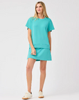 A woman wearing a aqua colored soft material skort with a matching top.