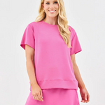 A woman wearing a pink soft fabric skort and a matching top.