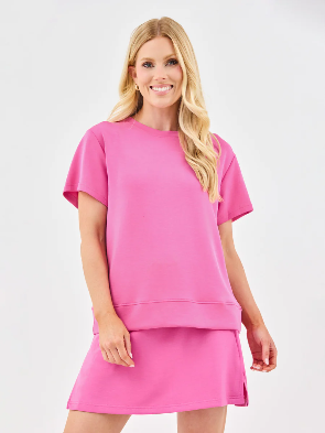 A woman wearing a pink soft fabric skort and a matching top.