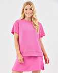 A woman wearing a pink soft fabric skort and a matching top.