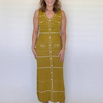 Woman wearing a green sleeveless dress with white buttons against a white background