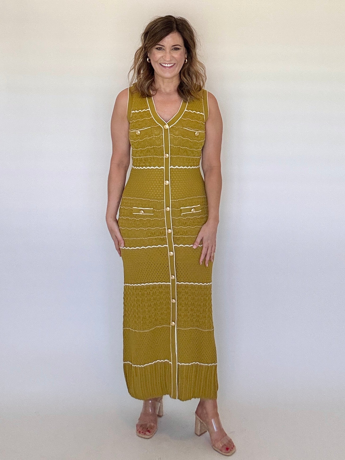Woman wearing a green sleeveless dress with white buttons against a white background
