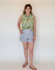 Woman wearing a floral sleeveless top and striped shorts against a white background