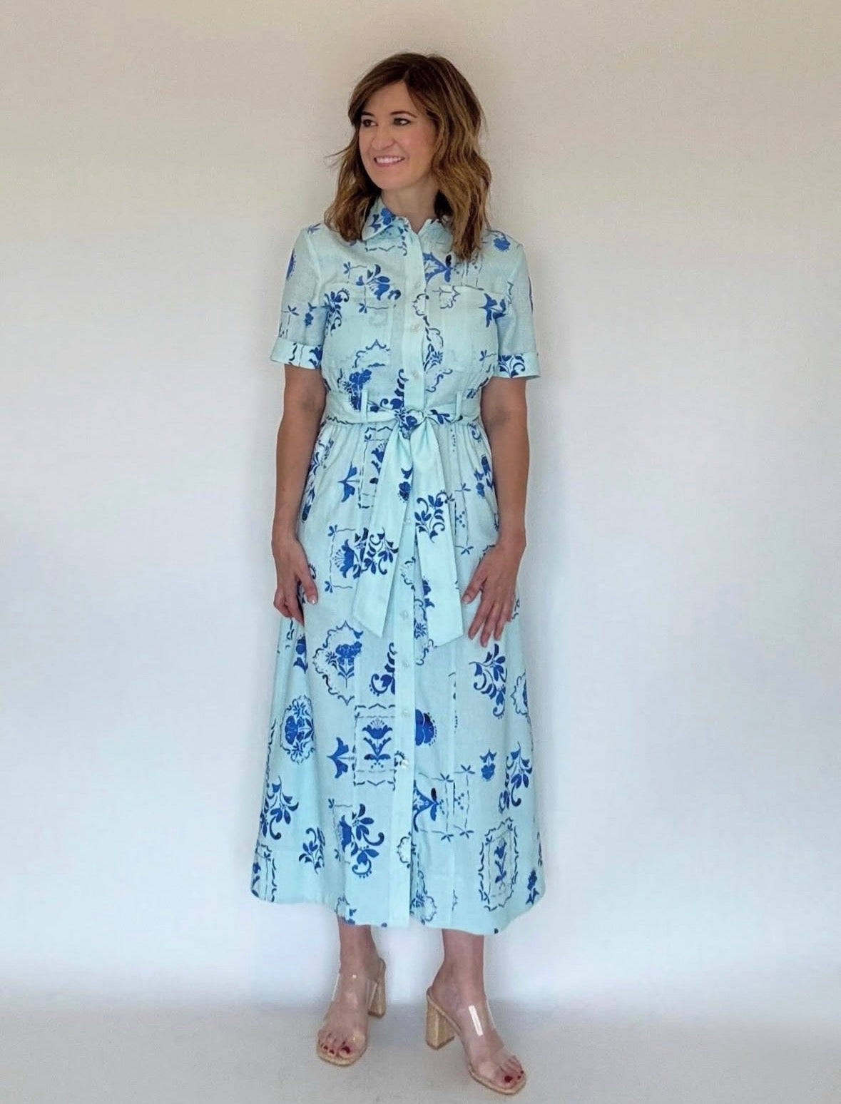 A woman wearing a blue and light blue floral print midi shirtdress with a belt.