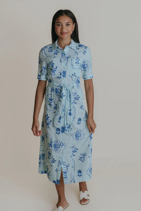 A woman wearing a light blue midi shirtdress with a tie belt.