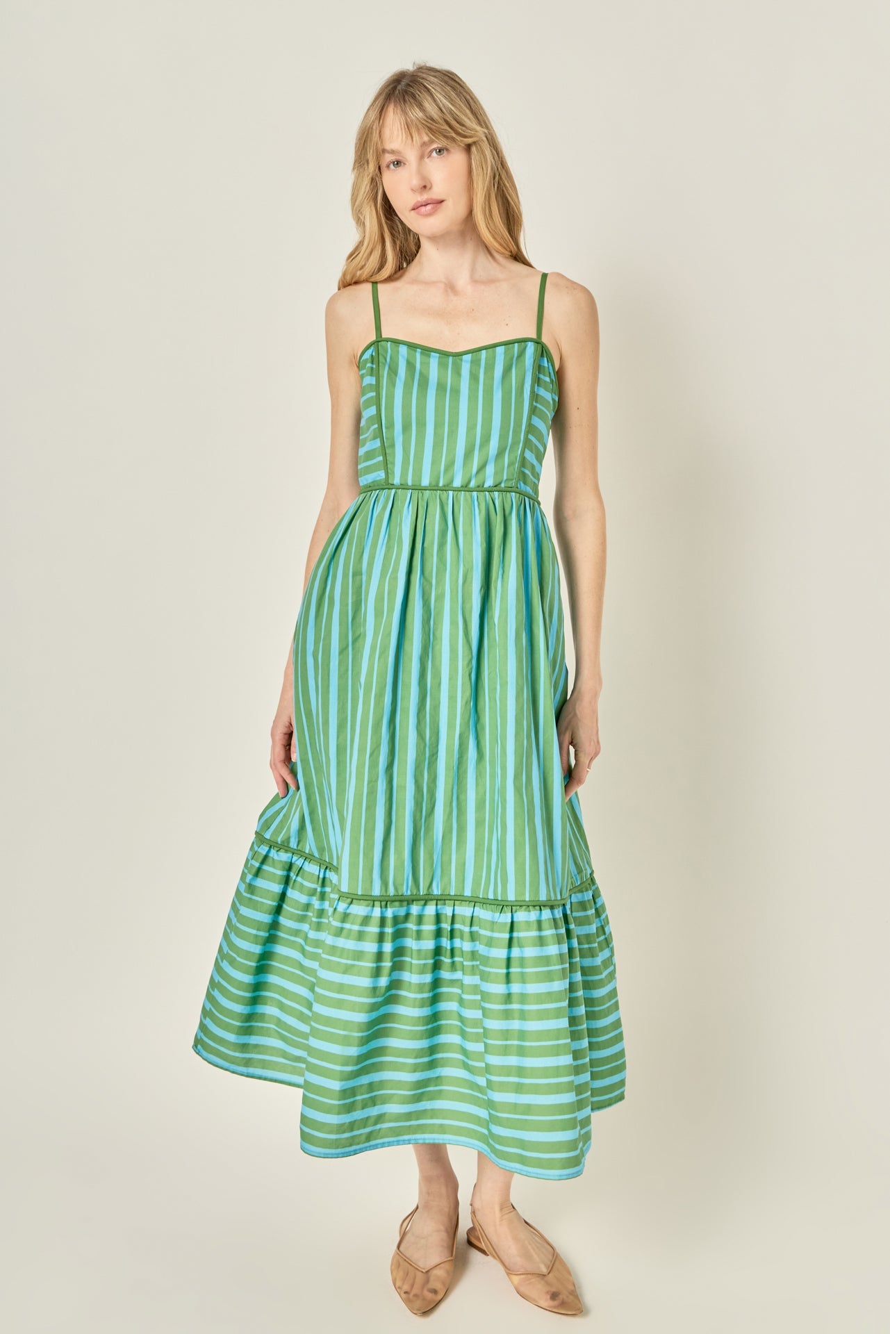 Woman wearing a green striped dress against a plain background