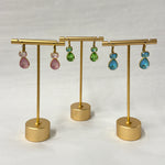 Gold earring stand with colorful earrings on a white background