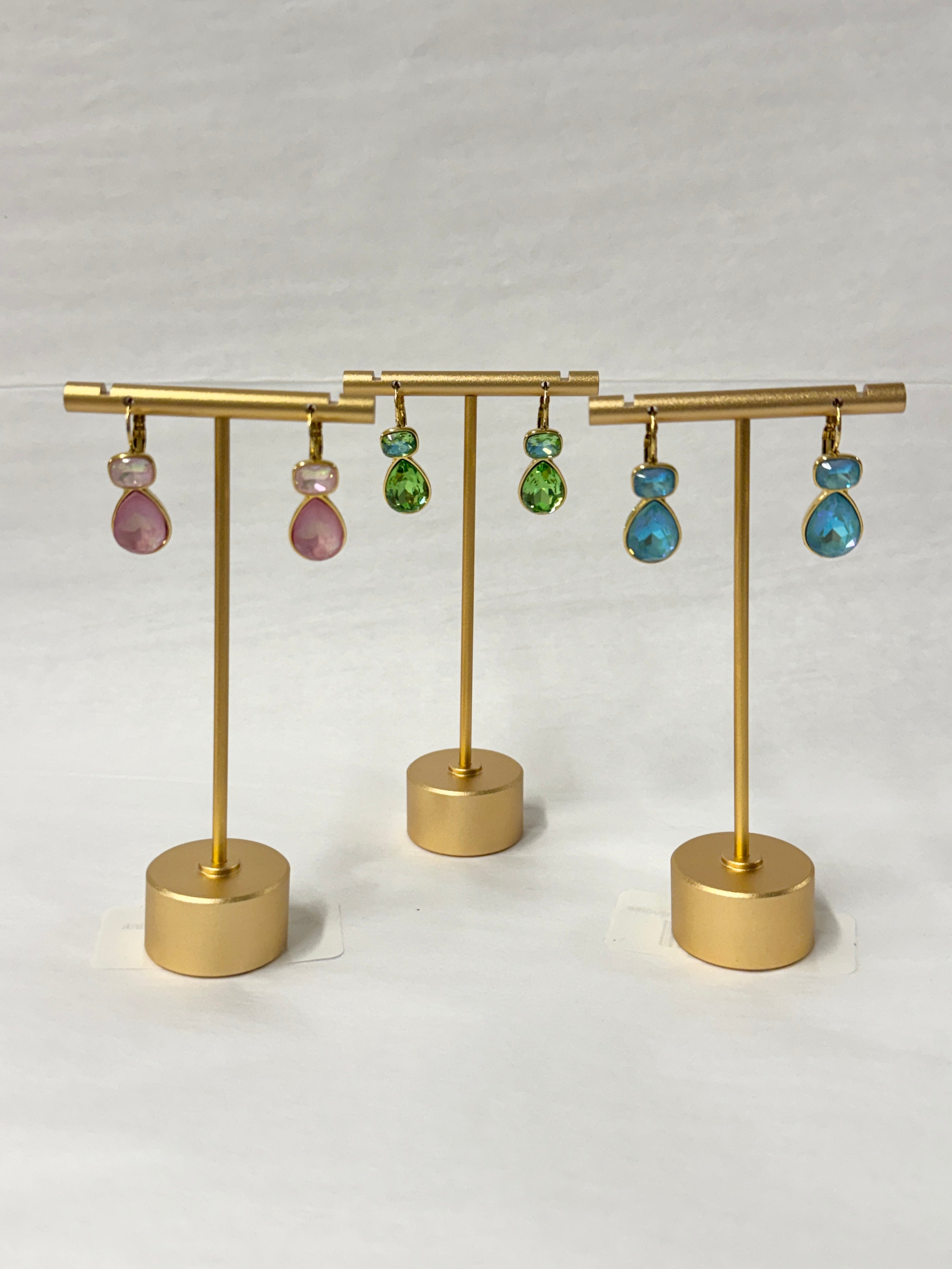 Gold earring stand with colorful earrings on a white background