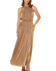 A woman wearing a shimmery gold halter neck maxi dress.