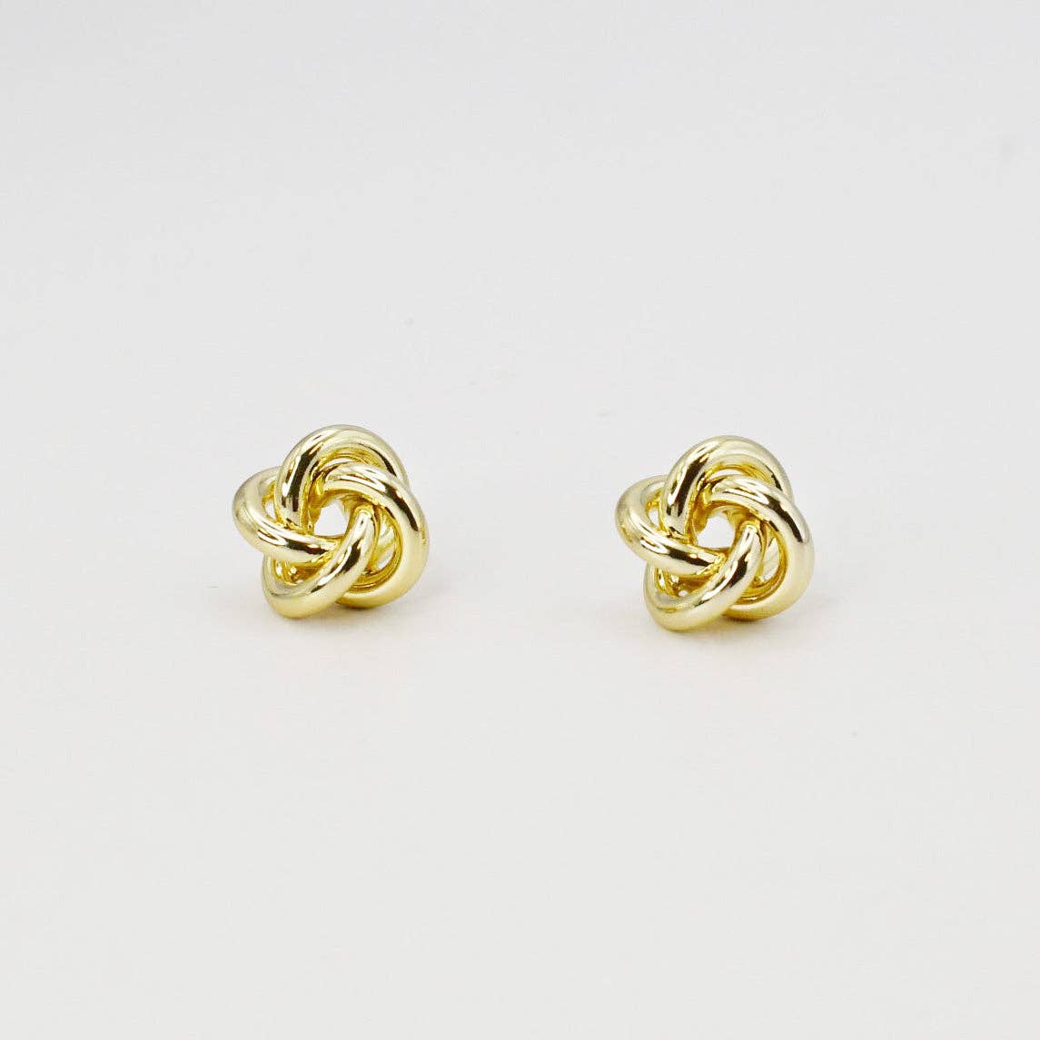 Pair of gold knot earrings on a light gray background