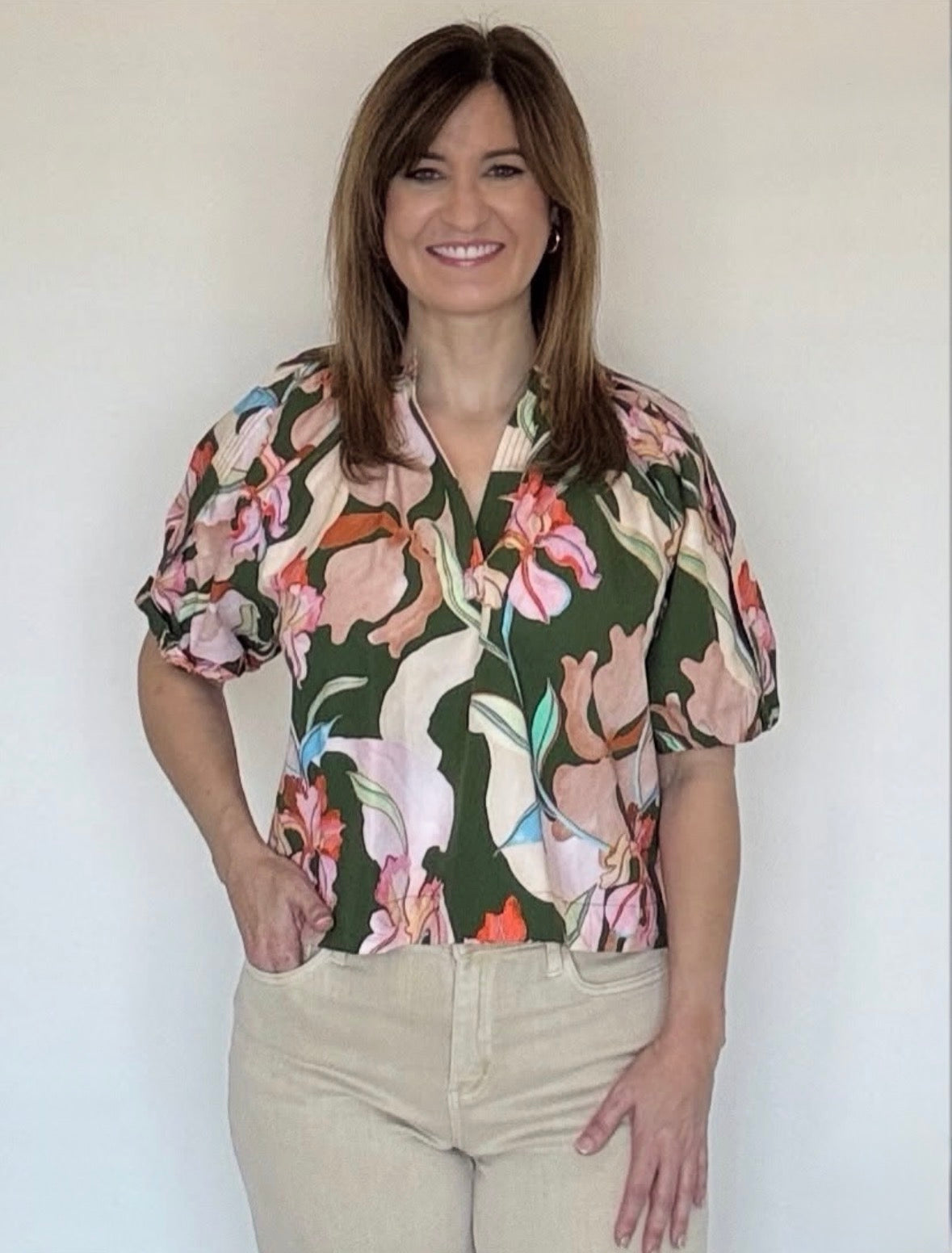 a woman wearing a green floral split neck short sleeve blouse.