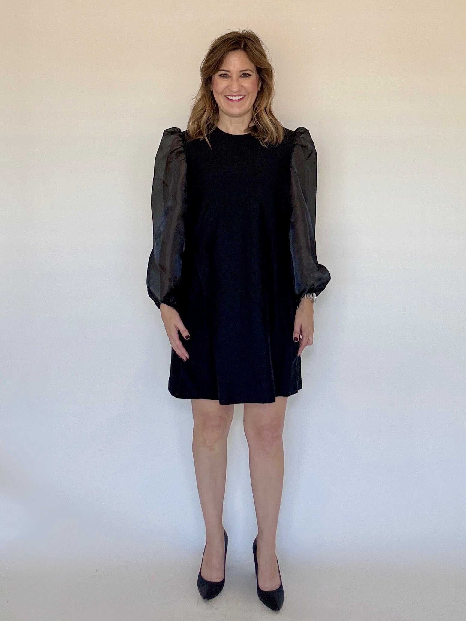 Black Puff Sleeve Mini Dress by Sail to Sable with sheer puff sleeves, styled with black pumps